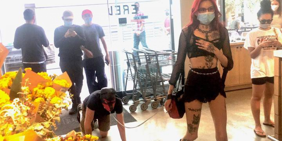 Dominatrix pictured walking sub on a lead through crowded supermarket